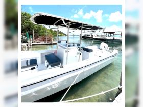 A pristine center console boat docked in clear waters, showcasing its sleek design and inviting seating — perfect for day trips and fishing adventures.