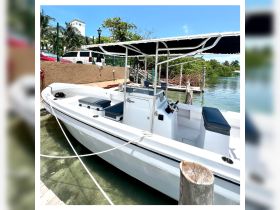 A sleek center console boat docked in clear waters, showcasing its spacious seating and helm — perfect for fishing trips or leisurely cruises.