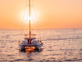 A couple enjoys a romantic moment aboard a catamaran at sunset, creating the perfect backdrop for unforgettable memories on the water.