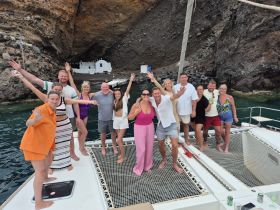 A lively group of friends celebrates aboard a catamaran, enjoying the stunning scenery and each other's company — perfect for memorable outings on the water.