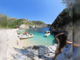 A stunning view of a secluded beach with boats anchored in crystal-clear waters, where guests enjoy a perfect day of sun and swimming.
