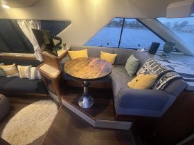 Cozy interior of a boat featuring a comfortable seating area and dining table, perfect for relaxing and enjoying meals while on the water.