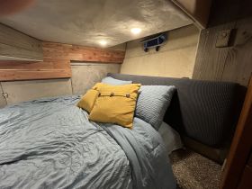 Cozy interior of a boat cabin featuring a comfortable bed with decorative pillows, perfect for restful nights on the water.