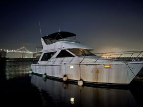 A sleek yacht docked at night, illuminated by the lights of a nearby bridge, showcasing a serene waterfront scene.