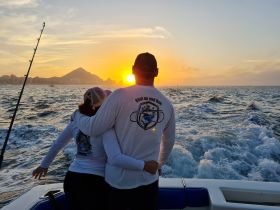 A couple embraces on a fishing boat at sunset, creating a romantic atmosphere perfect for memorable fishing trips and scenic views.