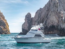 A fishing yacht navigates through stunning rock formations, showcasing the beauty of the coastline while underway.