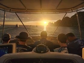 A group of fishermen enjoy a stunning sunset view from their boat, creating a perfect backdrop for a memorable fishing trip.