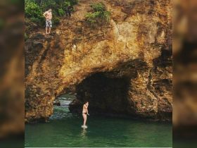 A thrilling moment captured as a woman prepares to jump into the water from a rocky cliff, showcasing the adventurous spirit of outdoor activities.