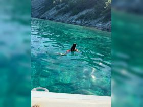 A person enjoys a refreshing swim in crystal-clear waters, surrounded by stunning natural scenery — a perfect summer getaway.