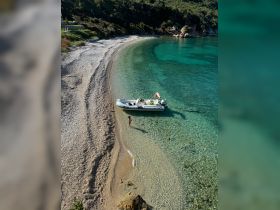 A serene beach scene featuring a person enjoying the clear waters near a boat, perfect for a relaxing day on the coast.