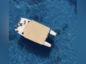 Aerial view of a group enjoying snorkeling around a catamaran in crystal-clear waters, showcasing the perfect blend of adventure and relaxation on the water.