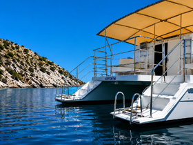 A stunning view of a catamaran anchored in calm waters, surrounded by rocky hills — perfect for exploring coastal destinations.