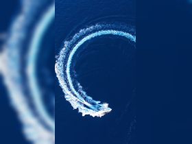 An aerial view of a speedboat making sharp turns in deep blue waters, showcasing the thrill of on-water adventures.