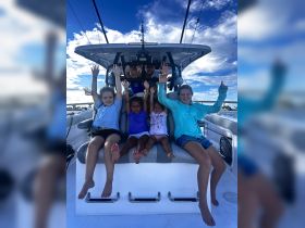 A joyful group of children celebrates aboard a boat, showcasing the fun and excitement of a day on the water.