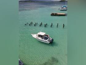 Aerial view of a sleek speedboat anchored in crystal-clear turquoise waters, showcasing the serene beauty of the coastline.