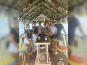 A lively group of friends gathers at a colorful bar on the water, enjoying a fun day out together — perfect for celebrations and socializing in a tropical paradise.