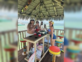 A lively group of friends enjoys cocktails at a tropical bar, celebrating together in a vibrant setting — perfect for unforgettable moments on the water.