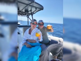 A cheerful couple enjoys refreshing coconut drinks on a boat, perfect for a sunny day at sea. Ideal for romantic getaways or fun adventures on the water.