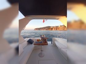 A cozy interior view of a boat featuring a dining area with a fruit platter and drinks, perfect for enjoying meals while cruising along scenic coastlines.