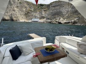 A cozy interior view of a boat featuring a table with fresh fruit and comfortable seating, perfect for enjoying snacks while cruising along scenic coastlines.