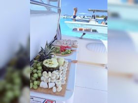A beautifully arranged platter of fresh fruits on a boat, perfect for enjoying snacks while soaking up the sun on the water. Guests can be seen enjoying the vibrant surroundings.