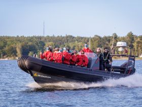 A group of adventurers enjoys a thrilling ride on a speedboat, showcasing the excitement of on-water activities in Stockholm's beautiful surroundings.