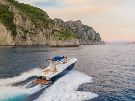 A stunning view of a boat cruising along a picturesque coastline, showcasing the beauty of the surrounding cliffs and tranquil waters — perfect for adventure seekers and nature lovers.