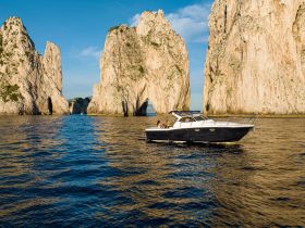 A stunning view of a boat navigating through iconic rock formations, with a couple enjoying the scenic coastline — a perfect representation of a memorable boating adventure.