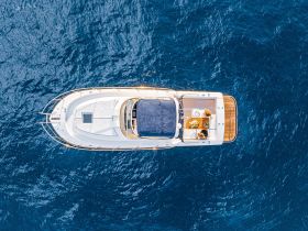 Aerial view of a luxurious yacht cruising through deep blue waters, showcasing its elegant design and inviting deck space.