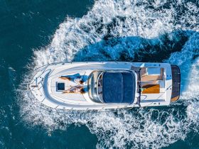 A couple relaxes on the deck of a yacht while cruising through vibrant waters, showcasing the perfect blend of luxury and leisure on the open sea.