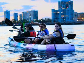 A lively group enjoys kayaking at sunset, showcasing the vibrant city skyline in the background — perfect for adventurous outings on the water.