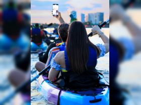 A group of friends enjoys a sunset kayaking adventure, capturing the moment with their phones — a perfect blend of fun and nature.