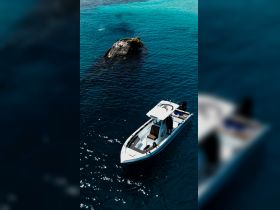 An aerial view of a boat near a shipwreck in stunning turquoise waters, showcasing a perfect adventure spot for exploration and diving.