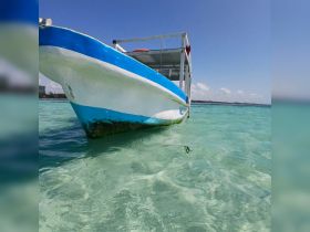 A close-up view of a colorful boat anchored in clear turquoise waters, showcasing its vibrant design against a picturesque backdrop.
