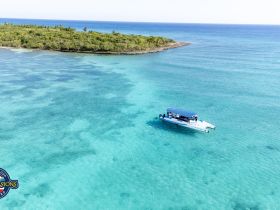 Aerial view of a catamaran navigating through crystal-clear turquoise waters, surrounded by lush greenery — perfect for exploring tropical destinations.