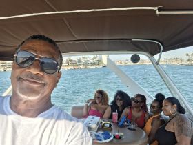 A joyful group enjoys a day on the water, celebrating with drinks on a pontoon boat — perfect for gatherings and fun outings.