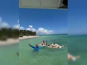 A lively group enjoys a fun day at the beach, floating in the water with drinks in hand — a perfect way to relax and celebrate under the sun.