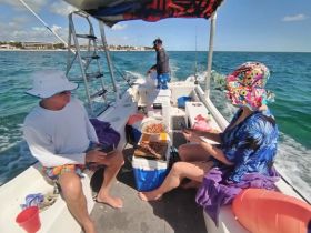 Guests enjoy a relaxing day on the water, sharing food and drinks aboard a boat — perfect for fishing trips or leisurely outings.