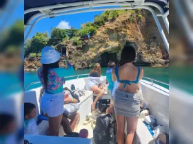 A group of friends enjoys a scenic boat ride, capturing the stunning cliffside views — perfect for adventure seekers and nature lovers.