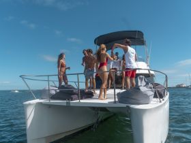 A lively group enjoys a celebration aboard a yacht, sharing drinks and laughter under the sunny sky — perfect for unforgettable summer parties on the water.