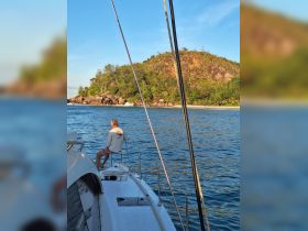 A serene moment on a boat with a guest enjoying the view of a picturesque island, perfect for relaxation and exploration in tropical waters.