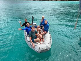 A cheerful group enjoys a snorkeling adventure on a small boat in stunning turquoise waters, capturing the essence of fun and exploration on the water.