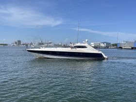A sleek yacht cruises through the water, showcasing its elegant design against a vibrant backdrop of the harbor.