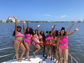 A vibrant group of friends celebrates on a boat, enjoying the sun and water in stylish bikinis — perfect for a fun day out on the water.