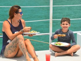 A woman and a child enjoy a delicious meal aboard a boat, showcasing a perfect family dining experience on the water.