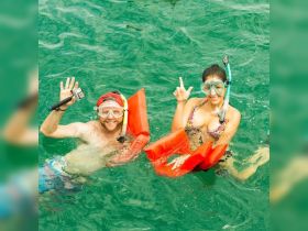 A cheerful couple enjoys snorkeling in vibrant turquoise waters, showcasing the fun and adventure of underwater exploration.
