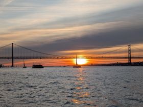 A stunning sunset view featuring a bridge and sailboats on the water, perfect for capturing the beauty of evening cruises.