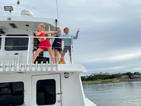 Three children joyfully pose on the deck of a boat, capturing a moment of fun and adventure on the water.
