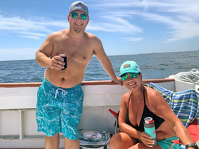 A cheerful couple enjoys drinks on a sunny day aboard a boat, capturing the essence of a perfect day on the water.