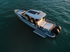 A stunning aerial view of a sleek speedboat gliding over clear waters, showcasing its modern design and spacious deck — perfect for luxury outings on the water.